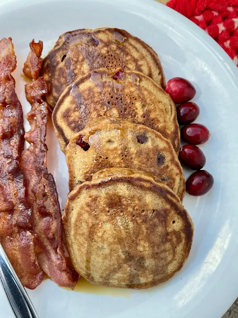 Plate of cranberry gingerbread pancakes with bacon on the side.