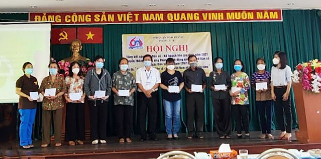Đại diện Chi cục Dân số - Kế hoạch hóa gia đình và lãnh đạo Phòng Y tế trao tặng thẻ Bảo hiểm y tế cho cộng tác viên dân số phường. (Ảnh: NS)