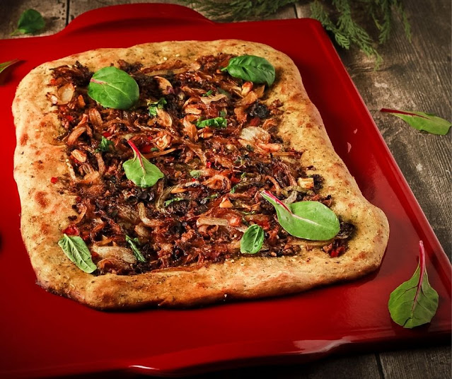 veggie pizza on red ceramic pizza stone