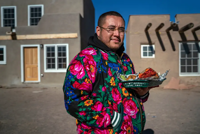 color photo of Yyan Rainbird Taylor holding a plate full of indigenous soul food dishes that Yapopup is known for. We meet him in the Ohkay Owingeh Pueblo, not far from his grandmother's home.