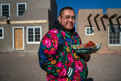 color photo of Yyan Rainbird Taylor holding a plate full of indigenous soul food dishes that Yapopup is known for. We meet him in the Ohkay Owingeh Pueblo, not far from his grandmother’s home.