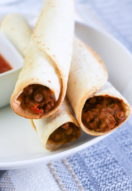 stack of three taquitos on a plate.