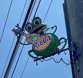 a frog sculpture attached to a telephone pole