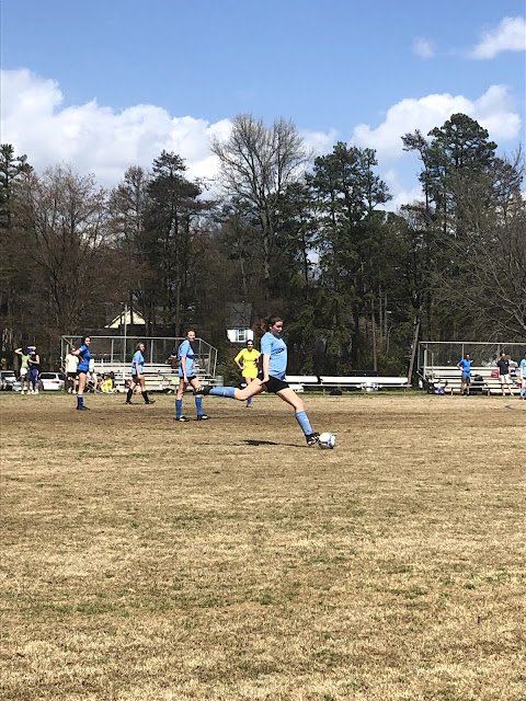 Elizabeth right before she kicks the ball. Her back foot is in the air getting ready to launch the ball while her front foot is planted.