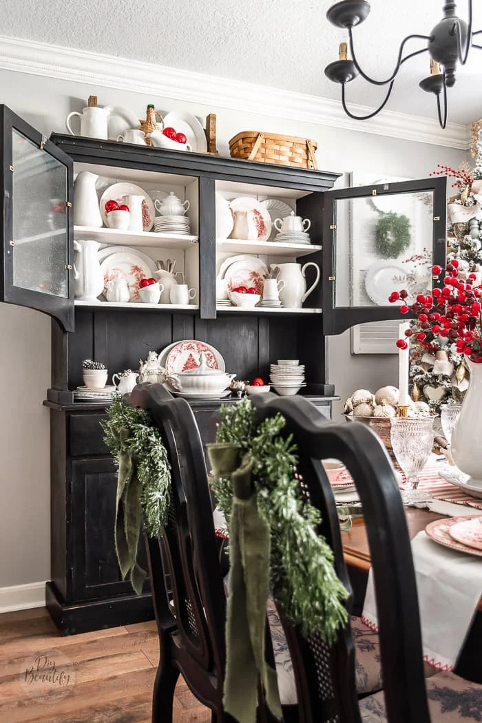 black hutch decorated with white ironstone and red ornaments for Christmas