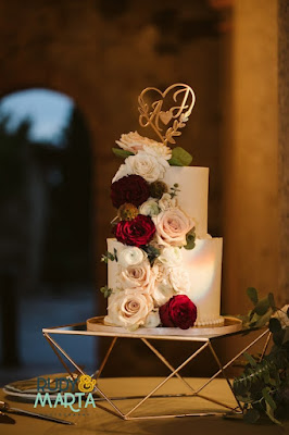 two tier white wedding cake with flowers on gold cake stand