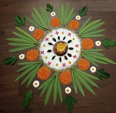 A colorful rangoli made with leaves, flowers and kitchen items