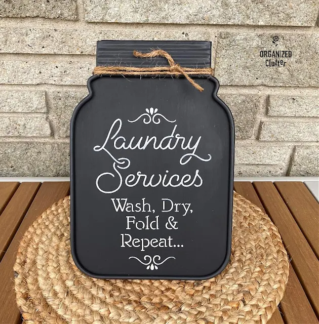 Photo of a jar shaped metal chalkboard with easel repurposed into a fun farmhouse laundry room sign.