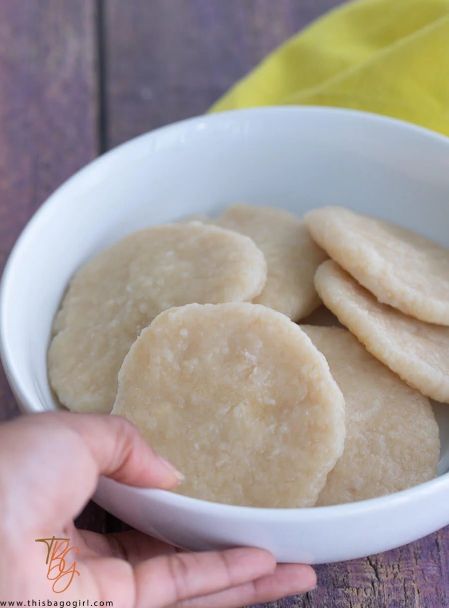 A hand holding a bowl of cassava dumplings.