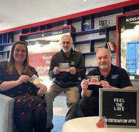 Woman and two men sitting and holding up Valentine's Day cookies