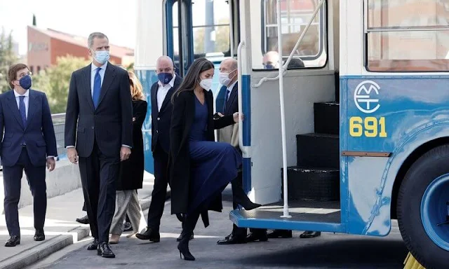 Queen Letizia wore a black a-line belted coat by Carolina Herrera, and blue v-neck dress by Massimo Dutti. Steve Madden boots