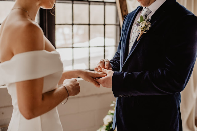 A groom inserting the wedding ring into his bride's finger.