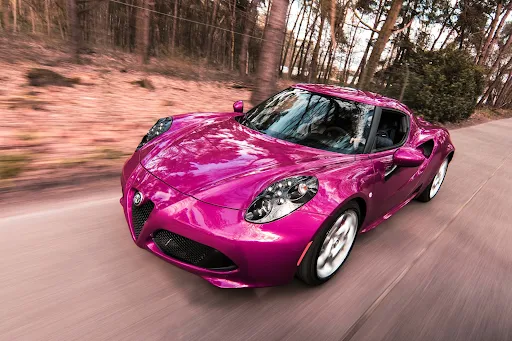 Free A sleek sports car driving fast on a forest road, showcasing speed and luxury. Stock Photo