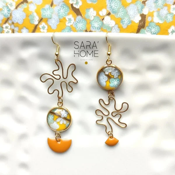 pair of asymmetric paper and brass dangle earrings decorated with yellow, aqua, and white floral paper and bright yellow glossy charms