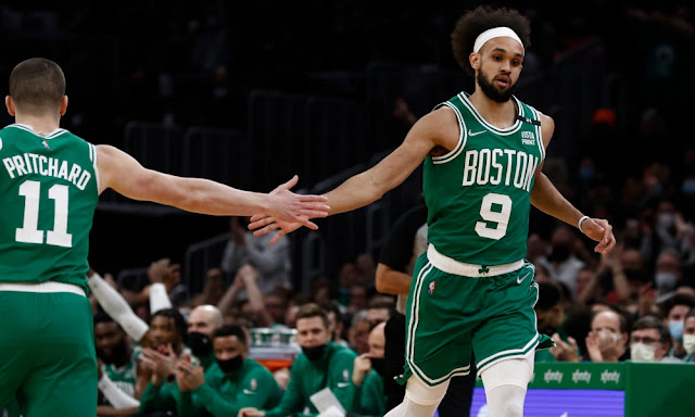 Derrick White high-fiving his Boston Celtics teammate Payton Pritchard while in the middle of a game