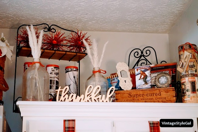 Antique milk bottles on top of cabinet with pampas grass inside, Christmas decorations on top of cabinet