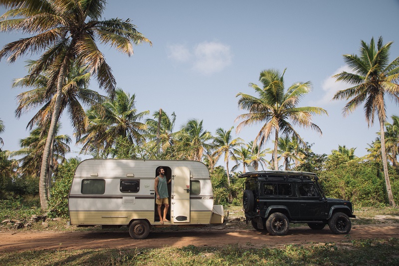 pessoa na porta de trailer, em frente a coqueiros - surftrip Pipa Baía Formosa