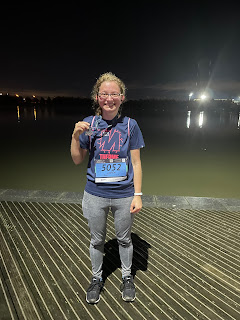 Me with my medal in the dark in front of a pond.