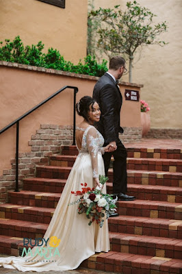 bride in dress holding flowers walking up the stairs with groom