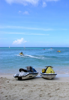 Jet skis on beach with sea in background.