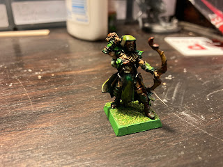 A painted elf with a bow, colored in greens and browns.
