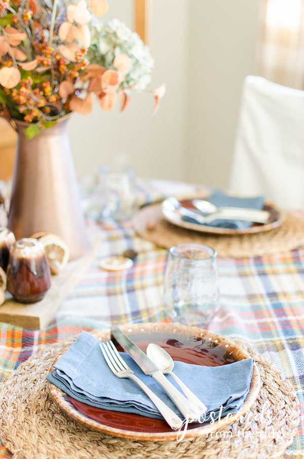 rustic fall place setting with vintage silver, brown drip glazed pottery dinner plate, blue napkin