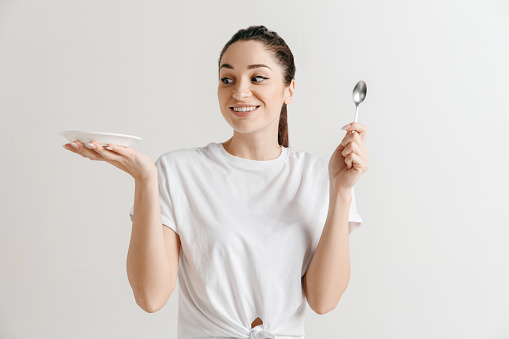 A woman holding a spoon and a plate and looking excited.
