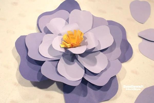 Step 4: Finish Flower Then add hot glue to the backside of the yellow center and the tear-drop petals and squeeze it right in the center of the layers of paper petals.