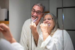 Two elderly people brushing their teeth.