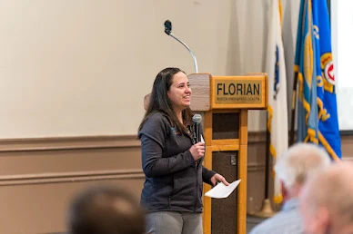 Woman speaking into microphone in front of stage