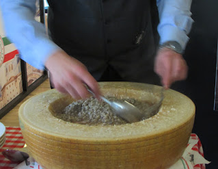 homem preparando risotto dentro de um queijo parmesão