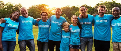 Group of people with arms around each other wearing shirts that say "volunteer"