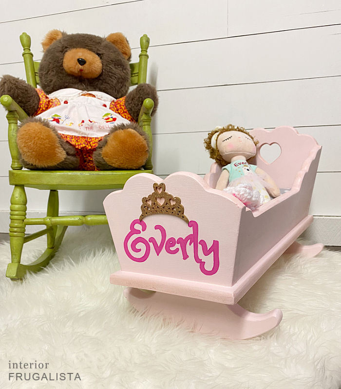 A vintage wooden doll cradle makeover painted a pretty pink and personalized with hand-painted child's name and DIY bedding fit for a little princess.