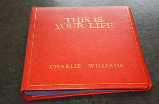 A red leather-bound book with 'This Is Your Life - Charlie Williams' embossed in gold