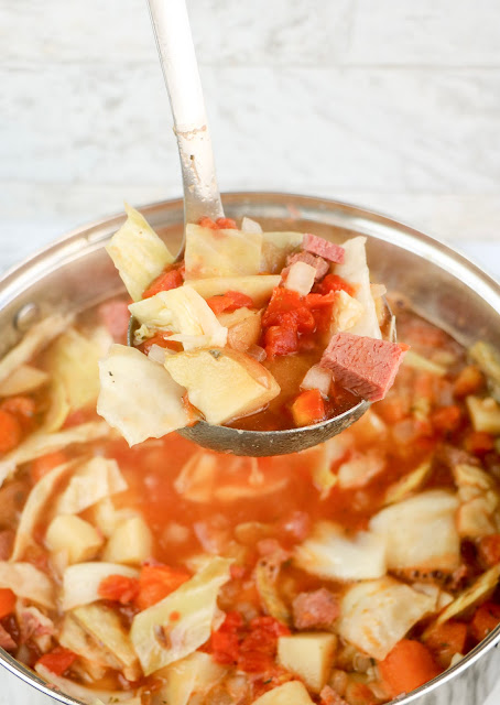 a full ladle of soup over a soup pot.