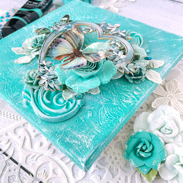 Mixed media canvas created with: Prima Marketing lace paper flowers, coffee break, Zella teal, magical love, finnabair jade impasto paint, grungy succulents, bindweed stencil; Reneabouquets patina lilac chipboard heart frame, into the mystic butterflies, gawdie girl glitter glass in ocean