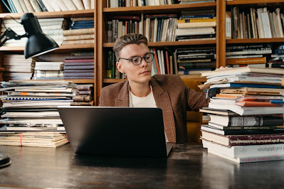 Man with laptop in front of shelf of books