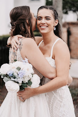 bride hugging bride holding flowers