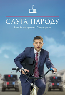 Photo of Volodymyr Zelenskyy on a bike, in a suit, holding a briefcase, appearing confused.