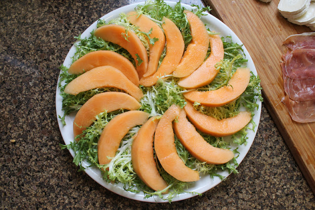 Arranging the melon slices on top of the greens on a large platter