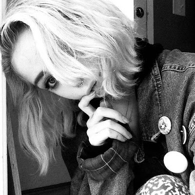 Blonde girl in a jeans jacket looking quizzical