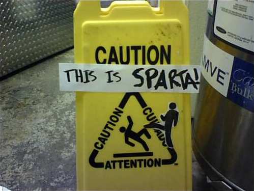 Caution: Wet Floor sign with stick man falling down altered to add stick man kicking him and words 'This is Sparta'
