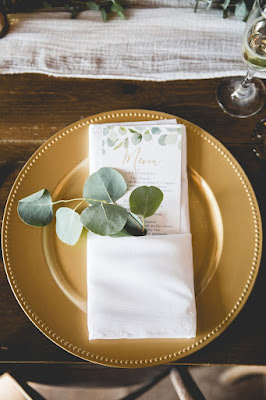 gold charger with white napkin and greenery