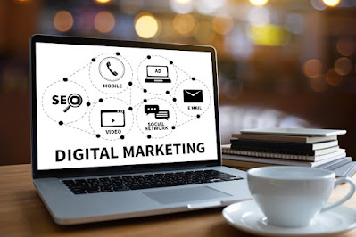 Digital marketing sign and symbols on a computer screen with notebooks and a coffee mug on the table.