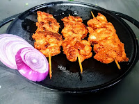 Serving chicken Angara kabab on sizzler plate with onion slices