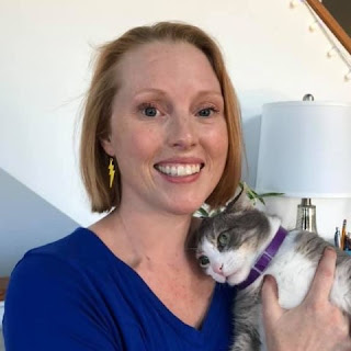 Headshot of Dr. Shew, a blonde white woman wearing a blue top, with her gray and white cat Sugar