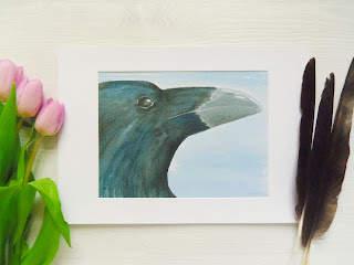 A raven profile in watercolours with a white background on white mountboard.