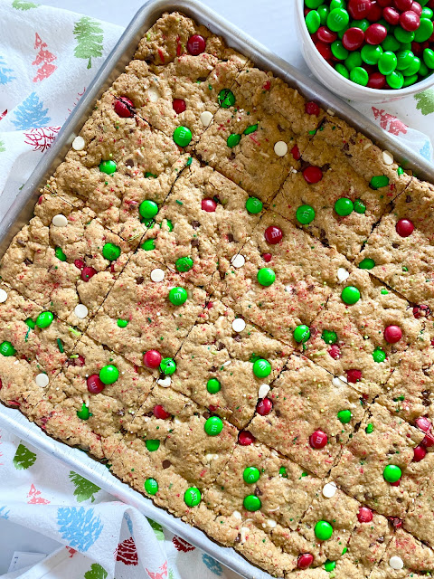 Jelly roll pan of monster cookie bars next to bowl of holiday M&M's