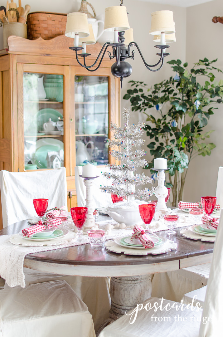 festive Christmas table decorations including red glasses and jadeite dishes with small silver tree