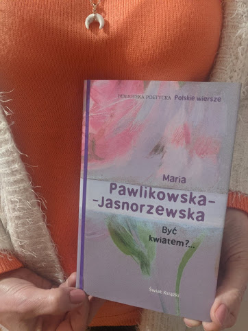 Tomik Być kwiatem?... Marii Pawlikowskiej-Jasnorzewskiej prezentuje czytelniczka w ceglastej bluzce i kremowym sweterku.